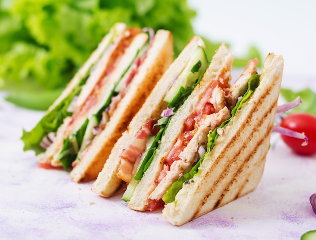 Club sandwich with chicken breast, bacon, tomato, cucumber and herbs