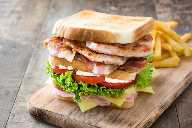 Club sandwich with frech fries on wooden table