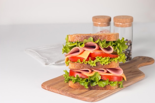 Клубный сэндвич с ветчиной, сыром, помидорами и листьями салата.