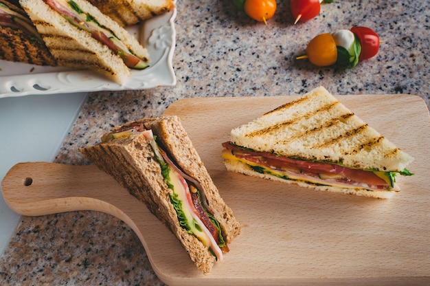 Club sandwich with ham, salami, smoked beef, cheese, lettuce and arugula.Toast sandwich preparation.