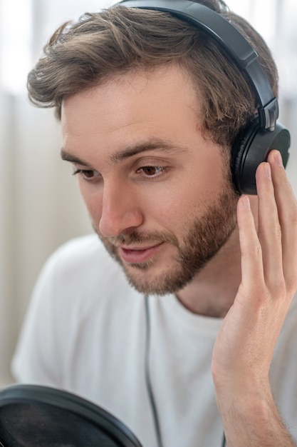 Clubhouse conference. A picture of a man in black headphones speaking in microphone