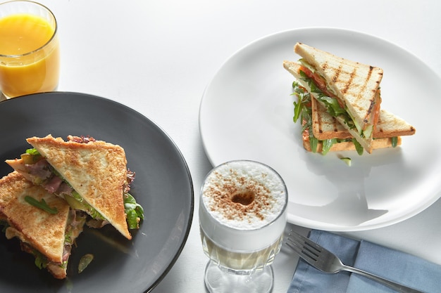 Clubsandwiches met verschillende vullingen en cappuccino op tafel