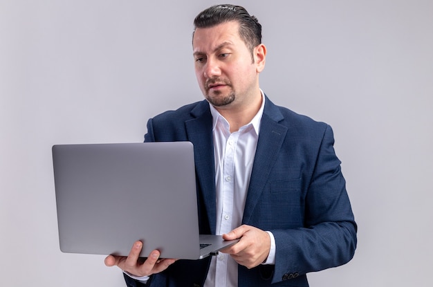 Clueless volwassen Slavische zakenman die laptop vasthoudt en bekijkt