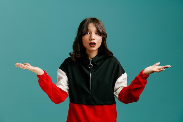 Clueless young caucasian woman looking at camera showing empty hands isolated on blue background