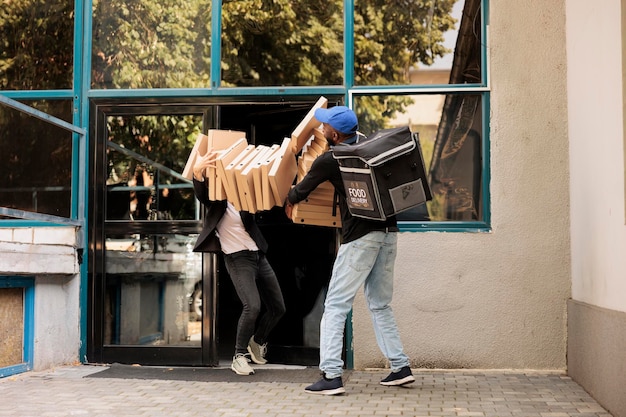 Clumsy pizzeria courier dropping pizza boxes pile at customer,\
shocked office employee catching falling fastfood packages stack.\
reckless deliveryman, bad food delivery service