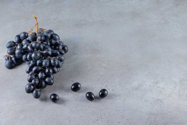 Cluster of fresh black grapes placed on stone background. 