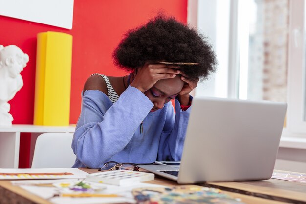 Photo clutching head. fashion designer clutching her head while feeling extremely tired after working all day