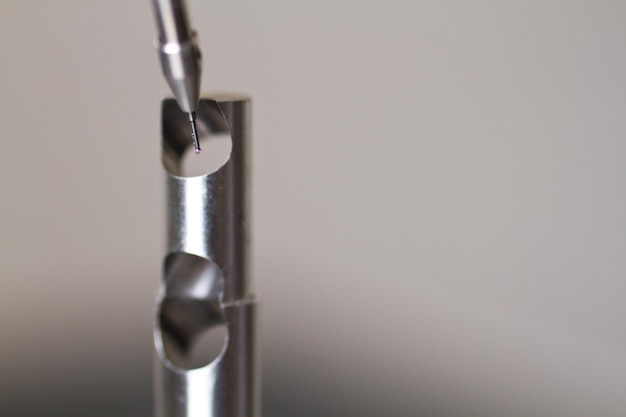 cmm programming probe by small metal part on white background closeup