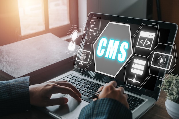 コンテンツマネジメントシステム (CMS) - バーチャル画面のバックグラウンドにコンテンツ管理システムのアイコンをインストールするノートパソコンを使用する人間の手