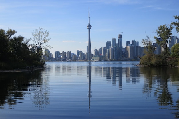 Photo cn tower amidst buildings in front of river against sky