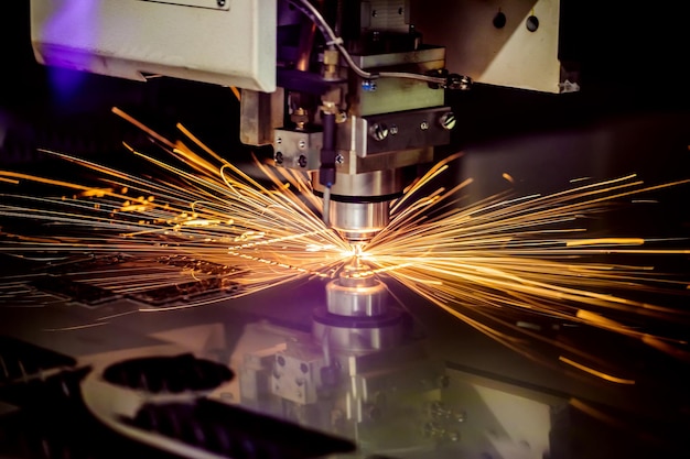 Taglio laser cnc del metallo, moderna tecnologia industriale. profondità di campo ridotta. avvertimento: riprese autentiche in condizioni difficili. un po' di grana e forse sfocato.