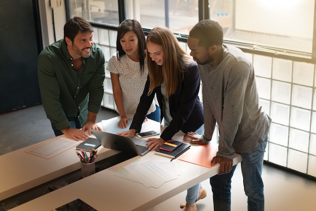 Co workers standing over desk going through presentation on computer