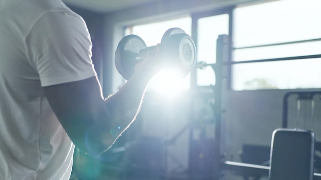 Coach bodybuilder performing an exercise with dumbbells