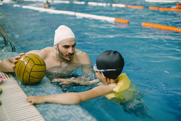 Coach leert kind in overdekt zwembad hoe te zwemmen en duiken. Zwemles, ontwikkeling van kinderen.