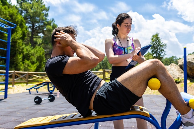 Coach monitoring situp exercise at outdoor park