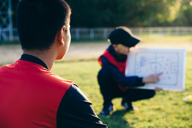 Foto allenatore che prepara una tattica per il calciatore adolescente asiatico.