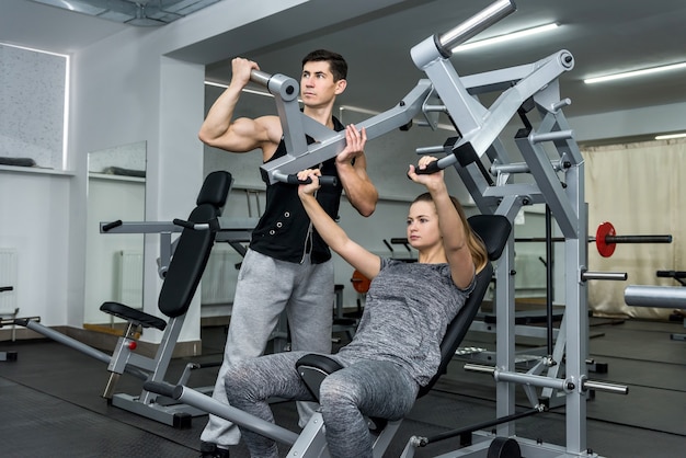 Coach training young and beautiful woman in gym