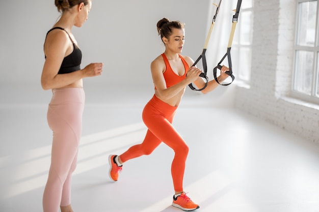 Coach trains a woman on TRX straps indoors