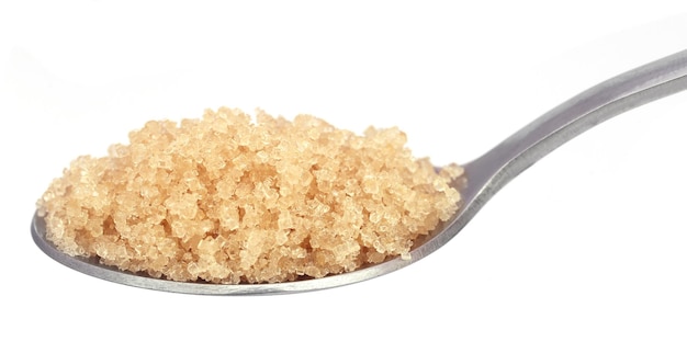 Coarse crystals of brown sugar in a silver spoon