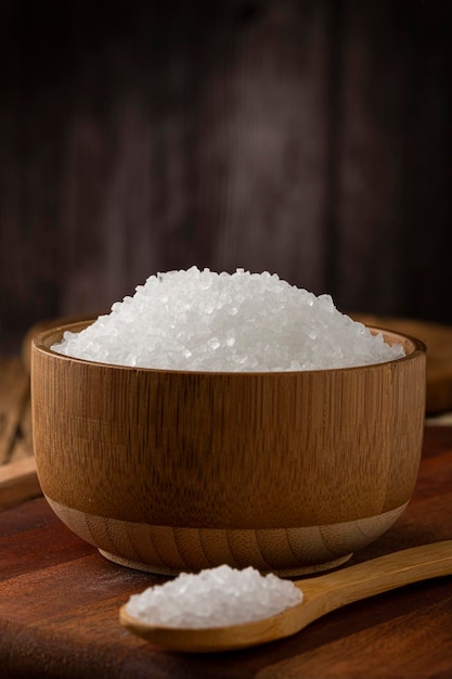 Крупная соль в миске на деревянных фоне