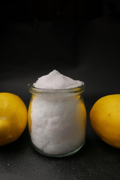 Coarse salt in a spoon and lemon on black background