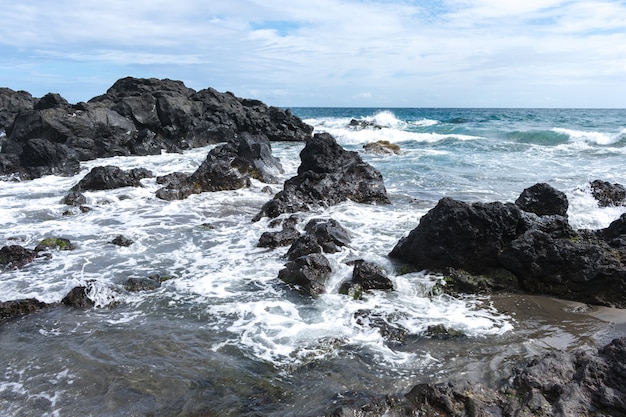 Coast rocks in azores. waves splashing on basalt rocks