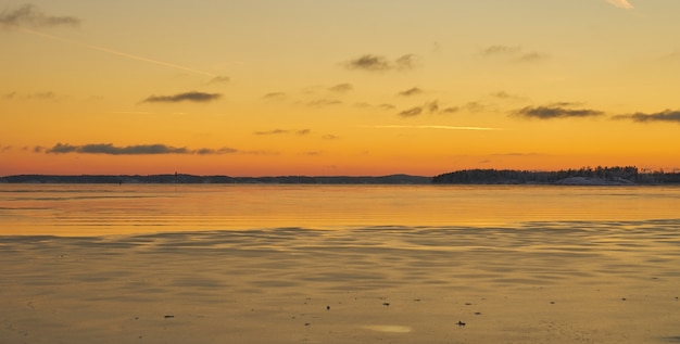 The coast of the sea in ice and in the snow at sunset