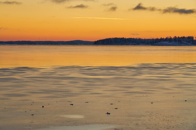 La costa del mare nel ghiaccio e nella neve al tramonto