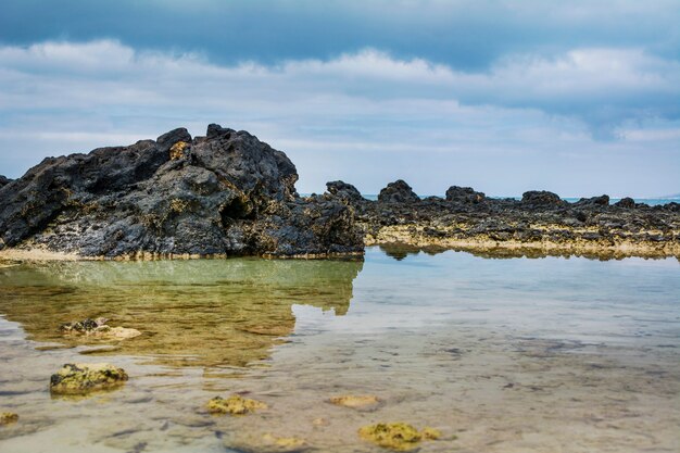 coastal landscape, rocks and sky reflected in the water. 