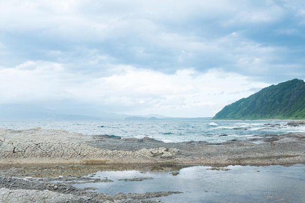 Coastal landscape with beautiful columnar basalt cliff on the wooded coast of Kunashir island