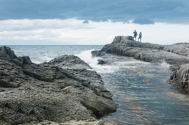썰물 관광객의 아름다운 원주형 현무암이 있는 해안 바다가 멀리 보입니다.