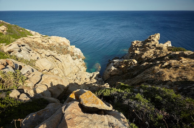 Береговая линия Капо Феррато с обрывом с видом на море, образованным гранитными скалами.