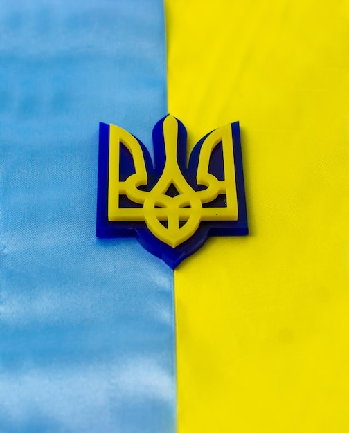 Photo coat of arms of ukraine on the background of the flag flag of blue and yellow stripes