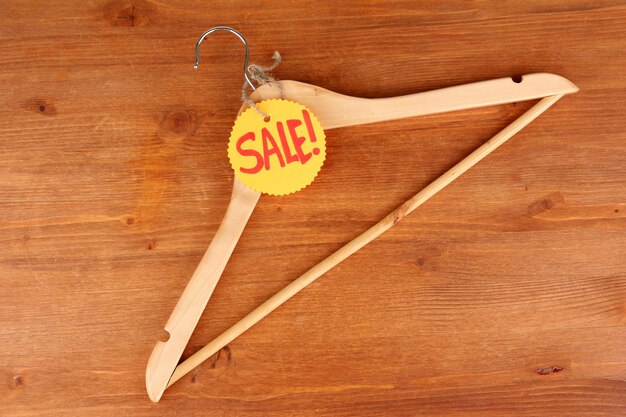 Coat hanger with sale tag on wooden background