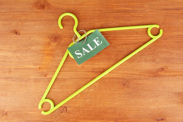 Coat hanger with sale tag on wooden background