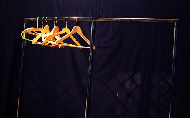 Coathangers hanging on rack against black backdrop