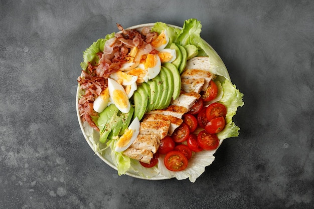 Cobb-salade met bacon-avocado-tomaat gegrilde kippeneieren op donkergrijze achtergrond Amerikaanse salade