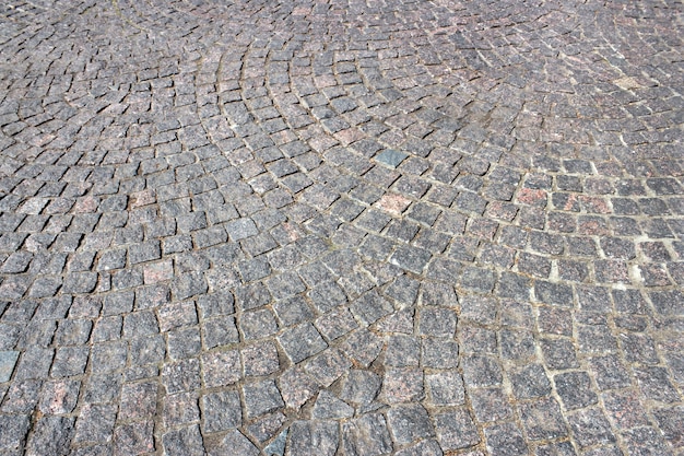 Cobbled pavement of gray granite close up as background