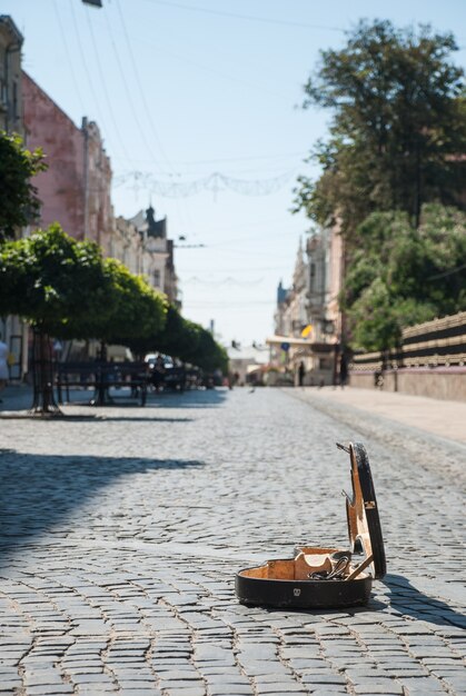 旧市街の通りの石畳。背景がぼやけている。手前にはチェロのオープンケースがあります。チェルノフツィ-ウクライナ西部の古代都市