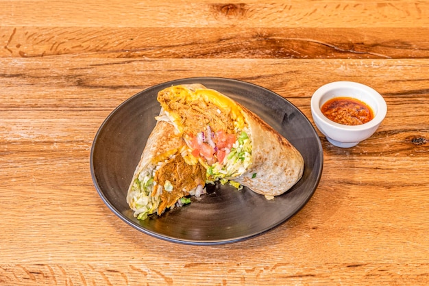 Cochinita pibil burrito with lots of white rice and lettuce cheddar cheese and grilled wheat tortilla with sauce to dip