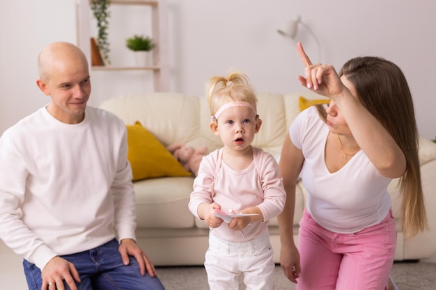 子供の女の子の頭に人工内耳を装着し、母親と父親の補聴器と難聴で遊んでいます