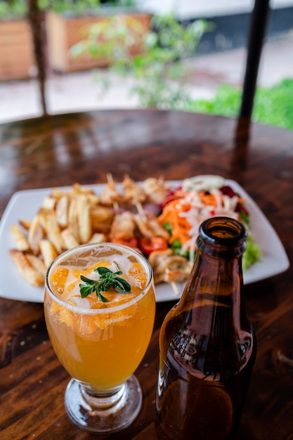 Foto cocktail accompagnato da un piatto di cibo su un tavolo di legno