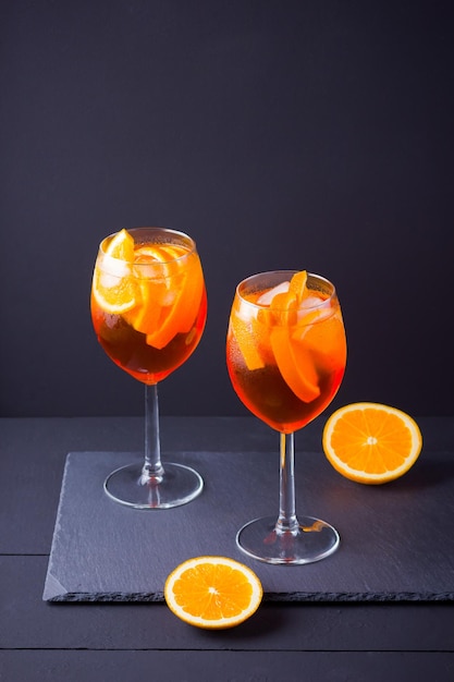 Фото Коктейль aperol spritz на темном фоне летний алкогольный коктейль с апельсиновыми фруктами и свежей мятой