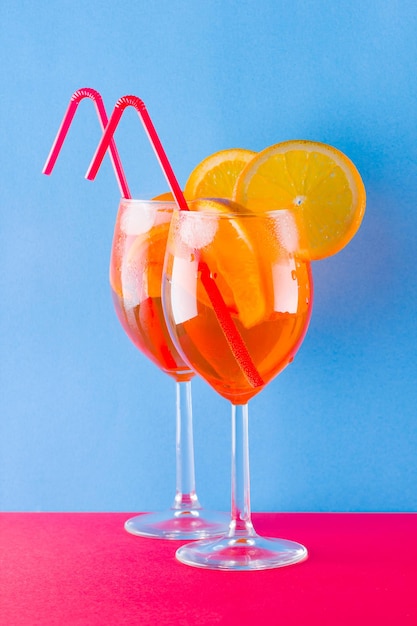Foto cocktail aperol spritz su sfondo rosso-blu aperol spritz con fette di arancione su sfondo colorato