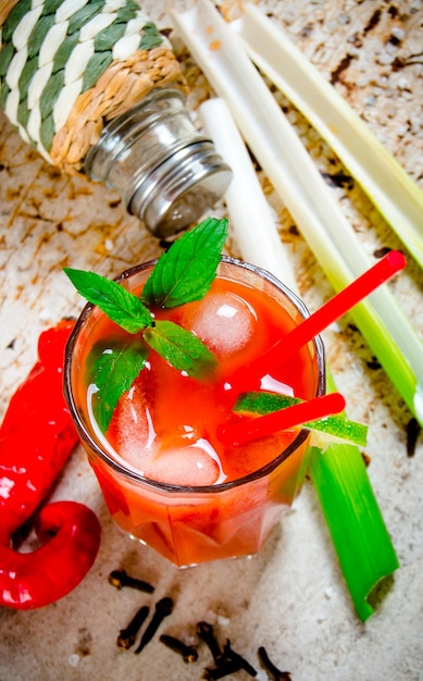 The cocktail bloody mary. Cocktails made of tomatoes, vodka, ice, lime, pepper, salt and snack with celery on rustic table