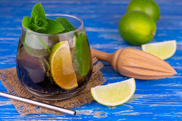 Cocktail cuba libre with lime rum mint and ice on an old blue wooden background