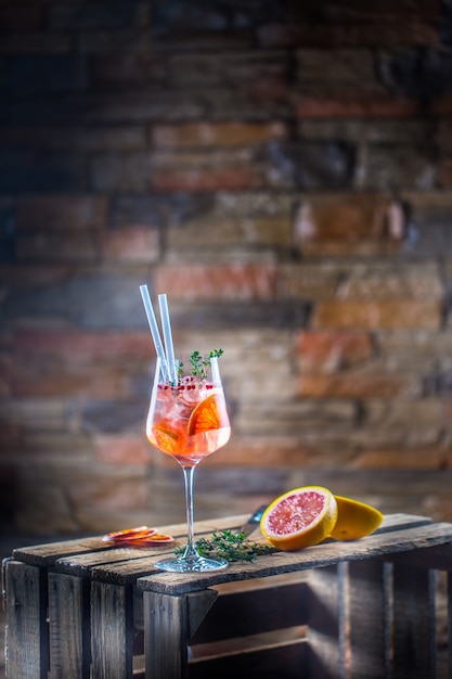 Cocktail drink on a old  wooden board Alcoholic beverage with tropical fruits red pepper and herbs