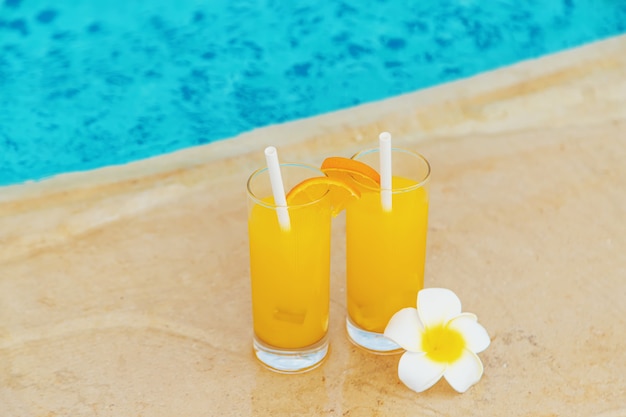 Cocktail in a glass by the pool and fruits