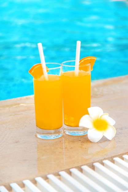 Cocktail in a glass by the pool and fruits