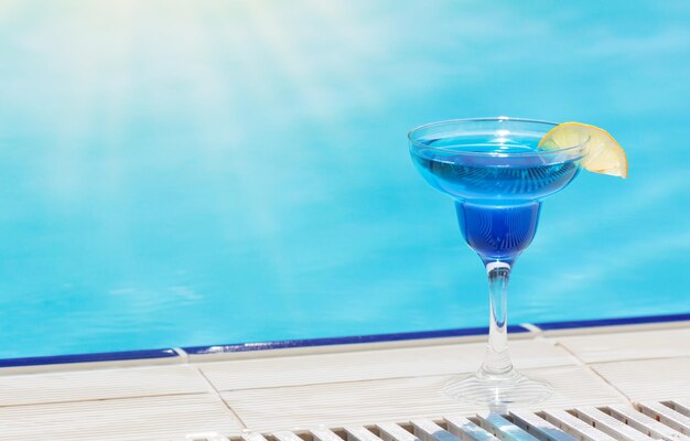 Cocktail glass at the edge of swimming pool